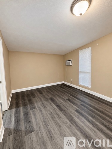 A room with wooden flooring and a window with blinds.