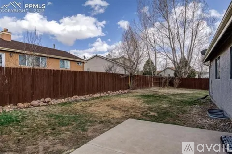 A backyard with a fence and a sidewalk.