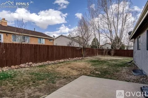 A backyard with a fence and a sidewalk.