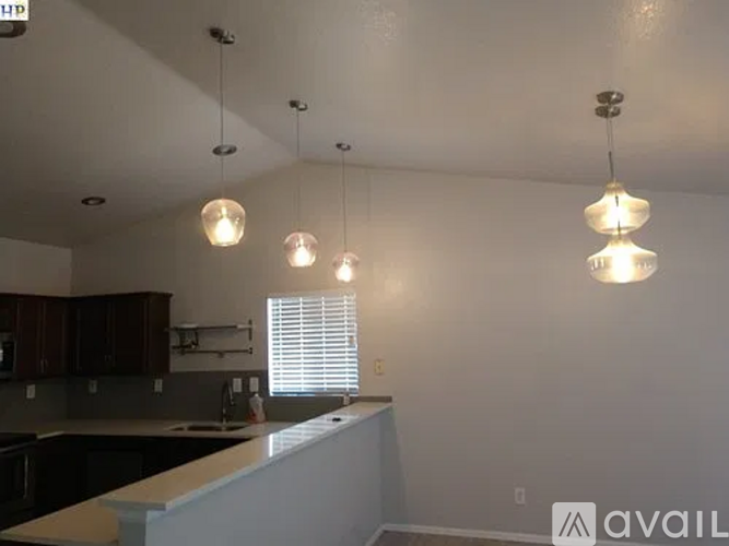 A kitchen with a white counter and three hanging lights.