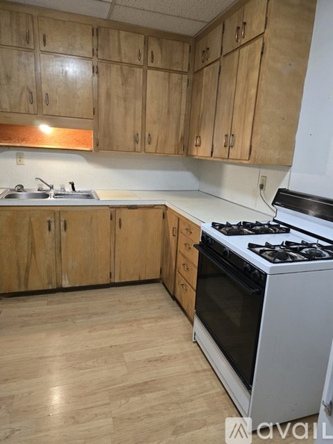 A kitchen with wooden cabinets and a white stove top oven.