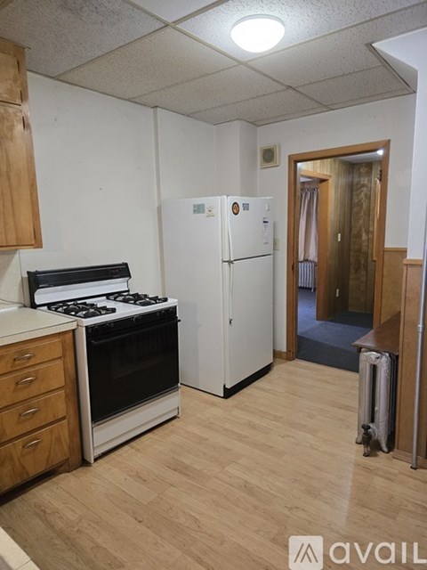 A kitchen with a stove, refrigerator, and wooden cabinets.