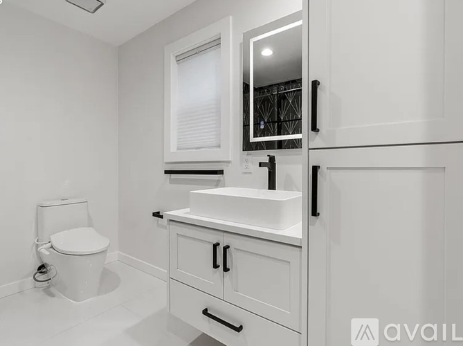 A white bathroom with a toilet, sink, and mirror.