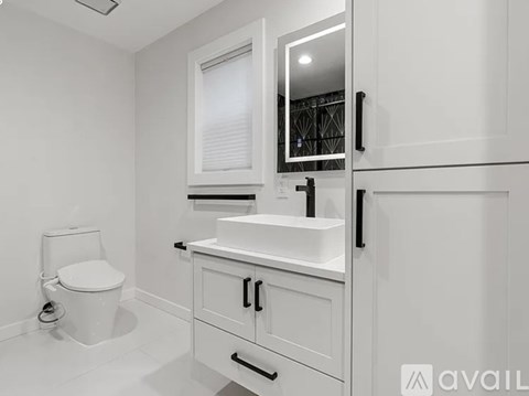 A white bathroom with a toilet, sink, and mirror.