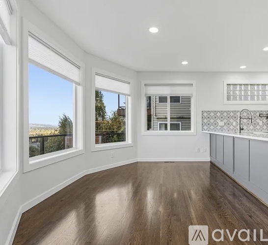 A spacious room with wooden floors and white walls.