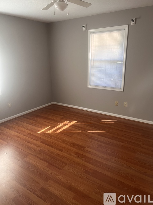 A room with wooden flooring and a window with blinds.