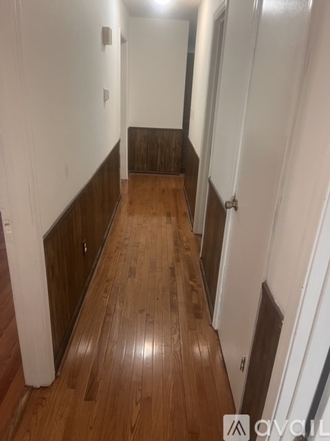 A hallway with wood floors and white walls.