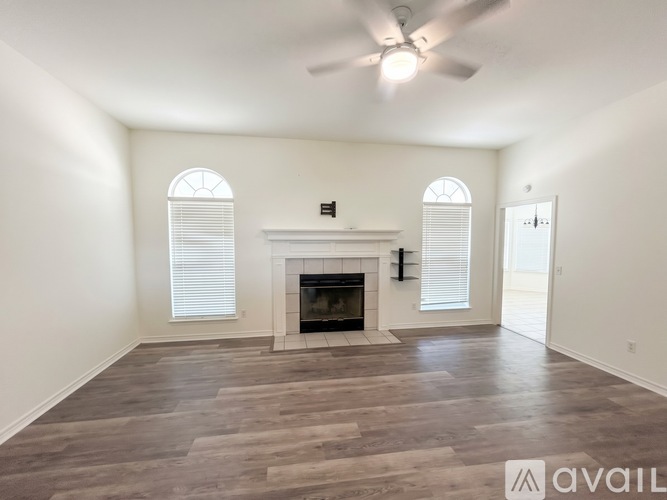 A spacious living room with a fireplace and a ceiling fan.