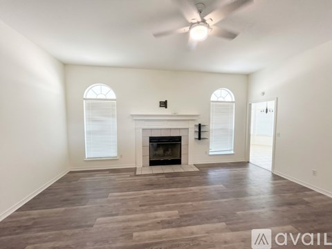 A spacious living room with a fireplace and a ceiling fan.