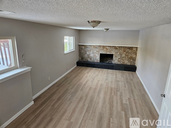 A room with wooden flooring and a stone fireplace.