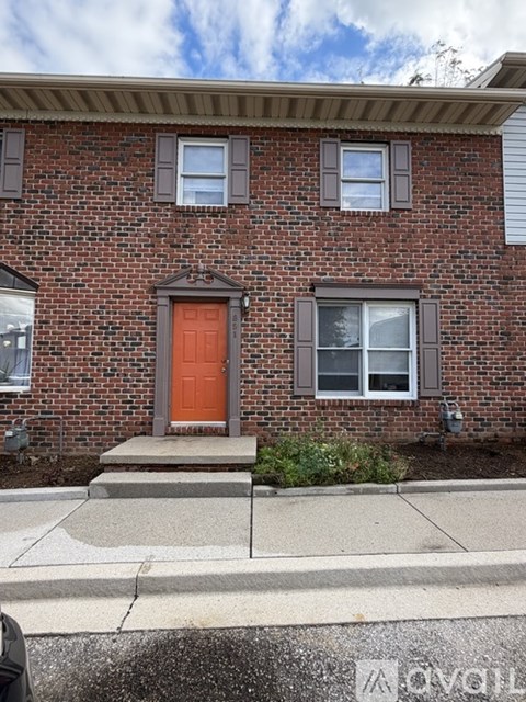 A red door is on the front of a brick house.