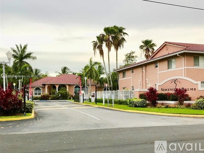 The image shows a building with the name "Serenity Palms" on it, surrounded by a fence and palm trees.