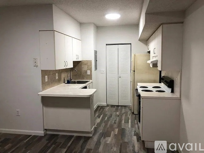 A small kitchen with a sink, stove, and cabinets.