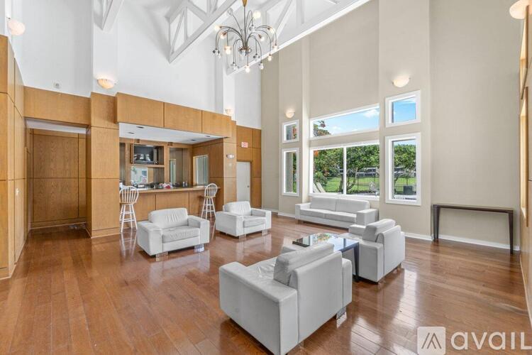 A spacious living room with white furniture and wooden floors.