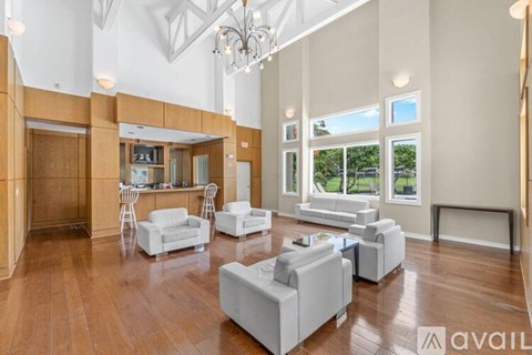 A spacious living room with white furniture and wooden floors.