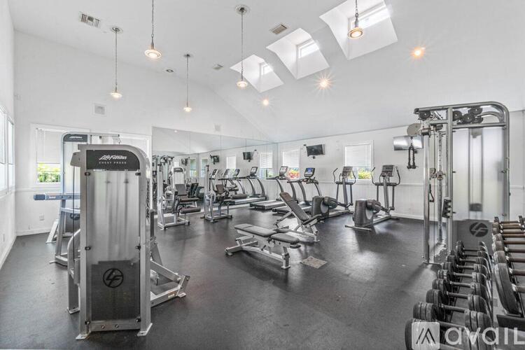 A gym with a variety of equipment including a squat rack, bench press, and a treadmill.