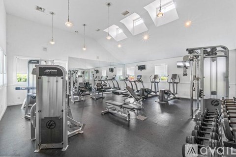 A gym with a variety of equipment including a squat rack, bench press, and a treadmill.