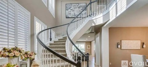 A spiral staircase with a metal railing and a painting hanging on the wall above it.