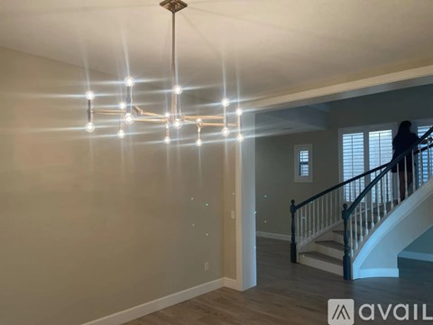 A modern chandelier hangs from the ceiling in a spacious room.