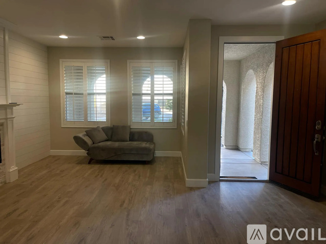 A living room with a grey couch and wooden floors.