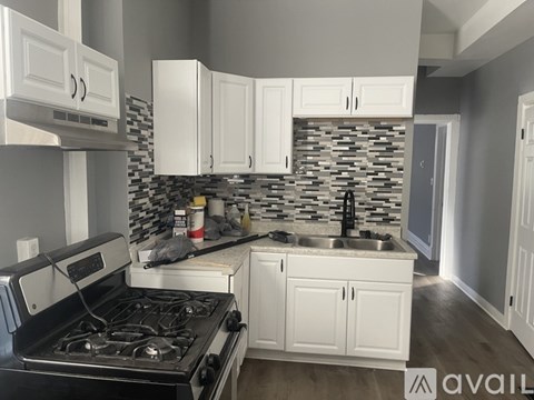 A kitchen with a black stove top oven and white cabinets.