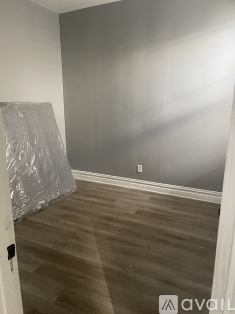 A room with wooden flooring and a wall covered in aluminum foil.