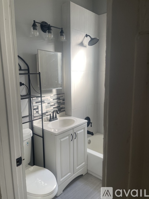 A white bathroom with a toilet, sink, and shower.