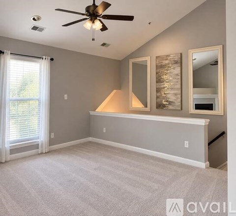 A room with a ceiling fan and a window with white curtains.
