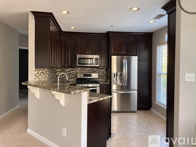 A kitchen with dark brown cabinets and a granite countertop.