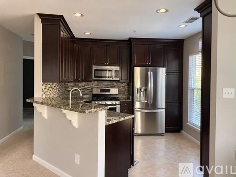 A kitchen with dark brown cabinets and a granite countertop.