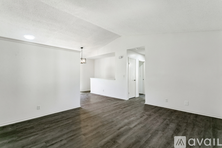 A spacious room with wooden flooring and white walls.