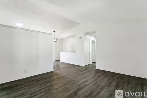 A spacious room with wooden flooring and white walls.