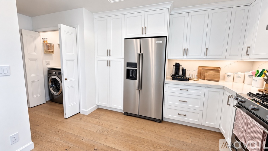 A kitchen with white cabinets and a stainless steel refrigerator.