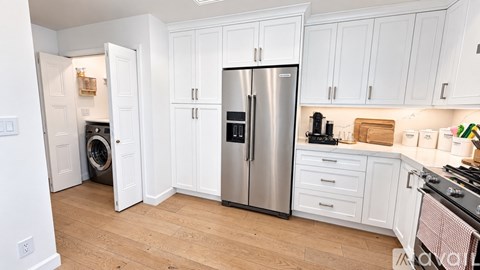 A kitchen with white cabinets and a stainless steel refrigerator.