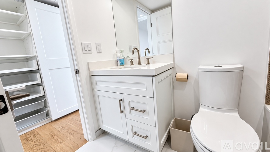 A white bathroom with a toilet, sink, and a cabinet.
