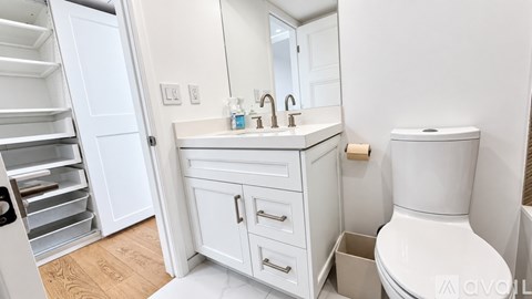 A white bathroom with a toilet, sink, and a cabinet.