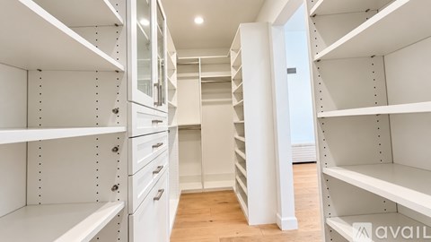 A white walk-in closet with shelves and drawers.