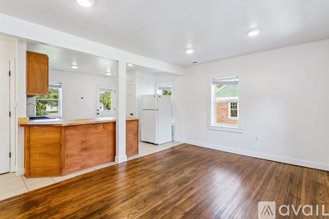 A spacious room with wooden floors and white walls.