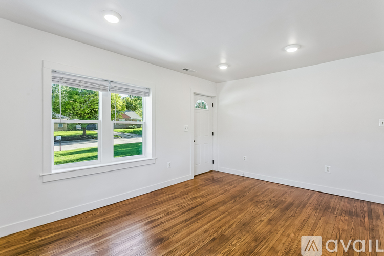 A room with wooden floors and a window showing a green outdoor area.