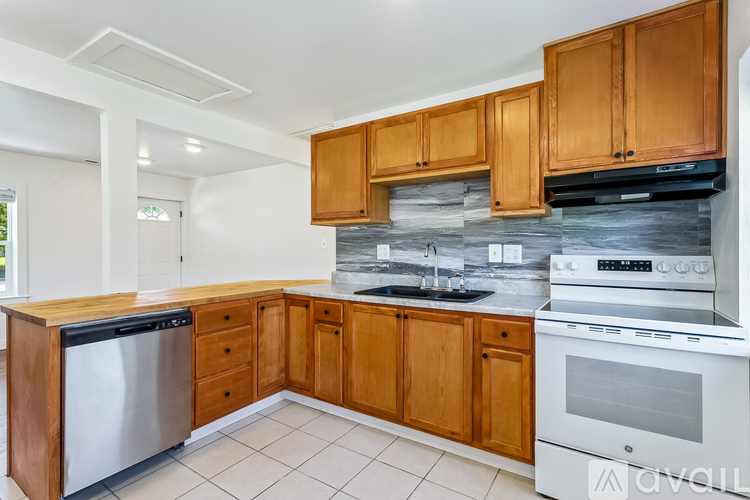 A kitchen with wooden cabinets and a stainless steel dishwasher.