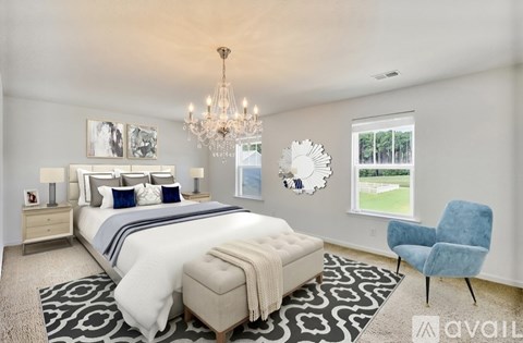 A bedroom with a large bed, a chandelier, and a blue chair.