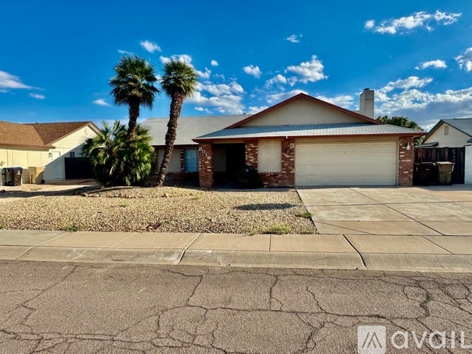 A house with a driveway and a palm tree in front.