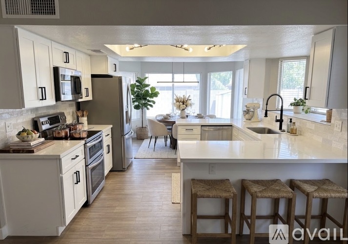 A kitchen with white cabinets and a large island with bar stools.