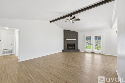 A spacious room with a fireplace and a ceiling fan.