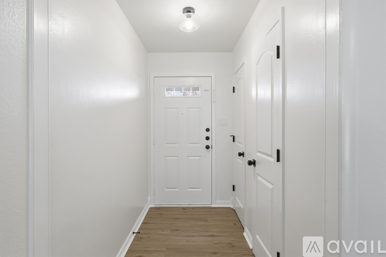 A hallway with a white door and wooden floor.
