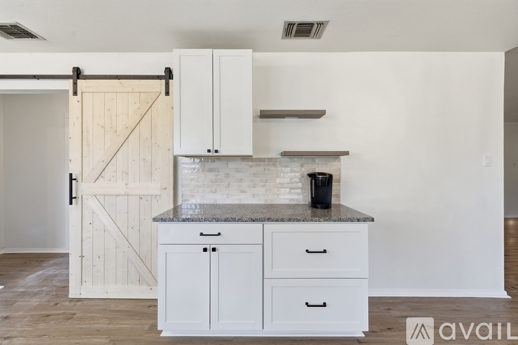 A kitchen with white cabinets and a granite countertop.
