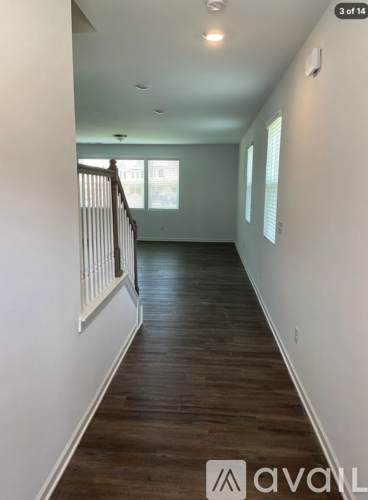 A long hallway with wood floors and white walls.