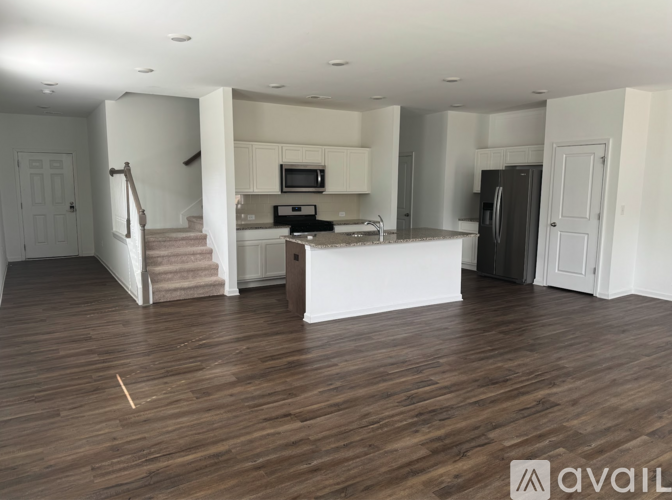A spacious living room with a kitchen in the background.