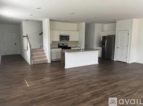 A spacious living room with a kitchen in the background.