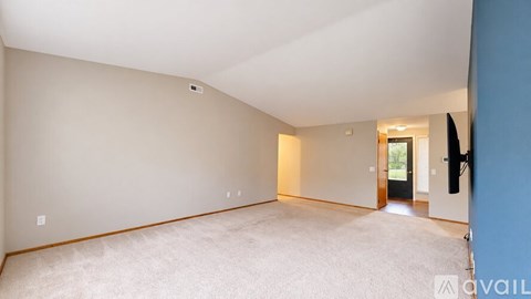 A spacious room with a carpeted floor and a doorway leading to another room.